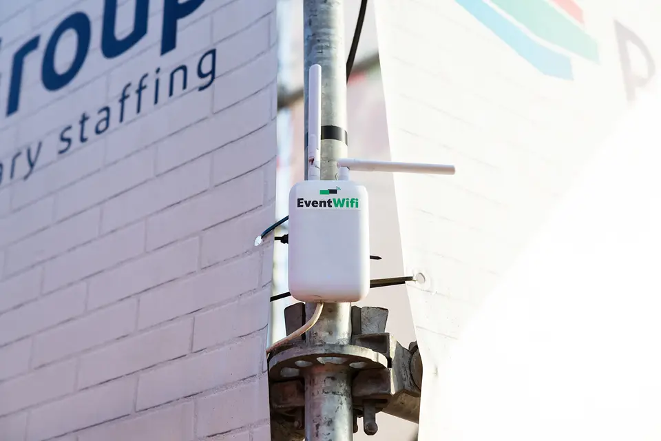 Accesspoint op de hoek Accesspoint van EventWiFi op een stellingbuis tegen de hoek van een gebouw op Rijvers Festival